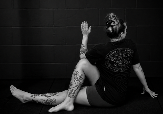Student in a seated spinal twist against a dark studio wall